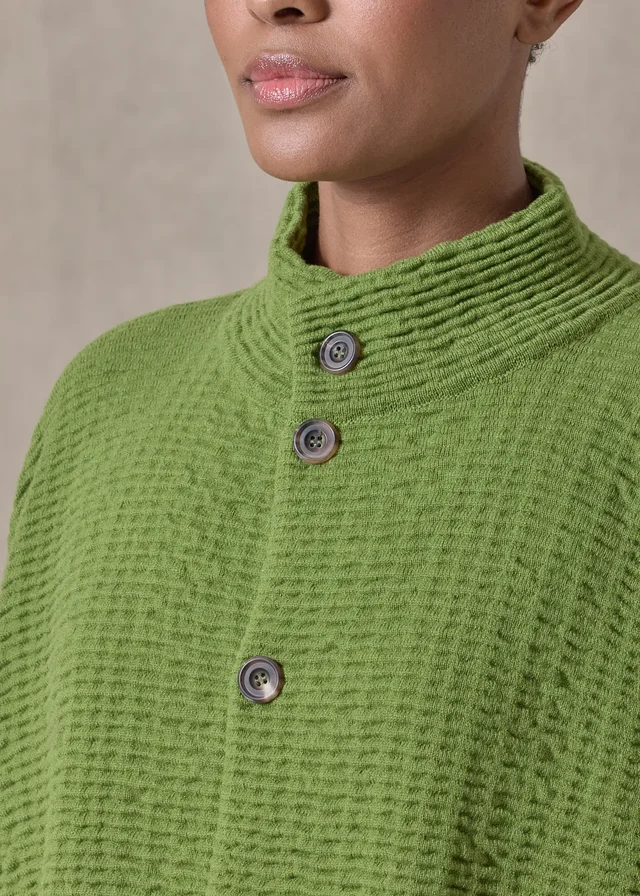 Green textured knitwear with a textured stand collar and three visible buttons, worn by a model.