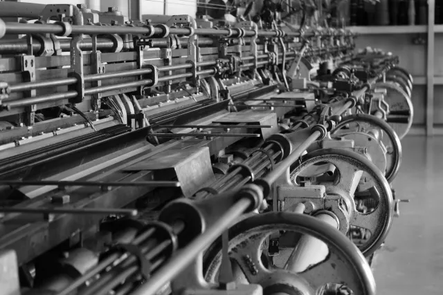 Black and white heritage photograph of traditional knitting machinery.