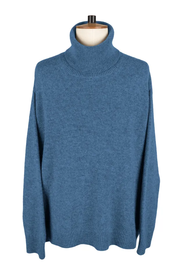 Denim blue roll neck sweater on a dress form, with long sleeves and ribbed collar, cuffs and hem.
